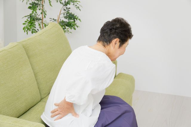 腰を押さえるシニア女性